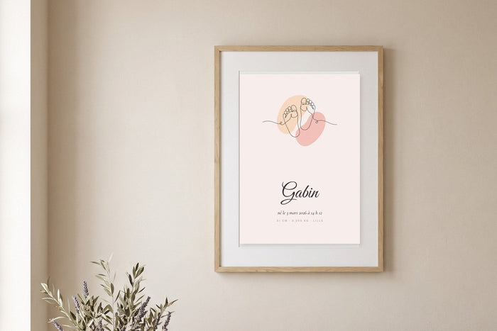 Affiche de naissance line art avec deux petits pieds et le prénom Gabin, encadrée sur un mur beige