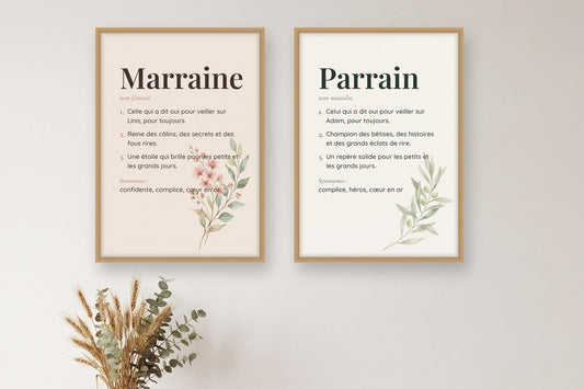 Affiches définition Marraine et Parrain encadrées côte à côte, fleurs roses et branche d'olivier, au-dessus d'un buffet en bois