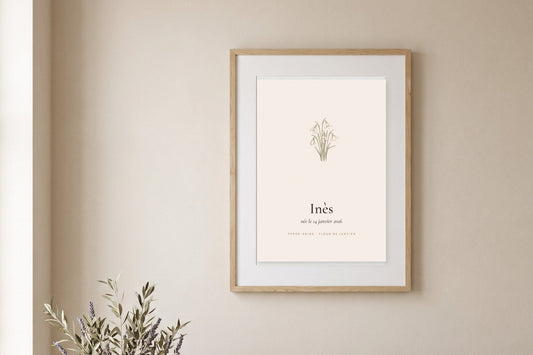 Affiche fleur de naissance avec une perce-neige à l'aquarelle et le prénom Inès, encadrée sur un mur beige